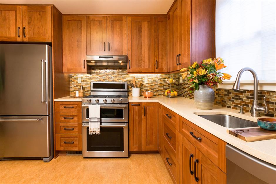 A small kitchen with stainless steel appliances, white cabinets, and a  natural light colored wood counter top Stock Photo - Alamy