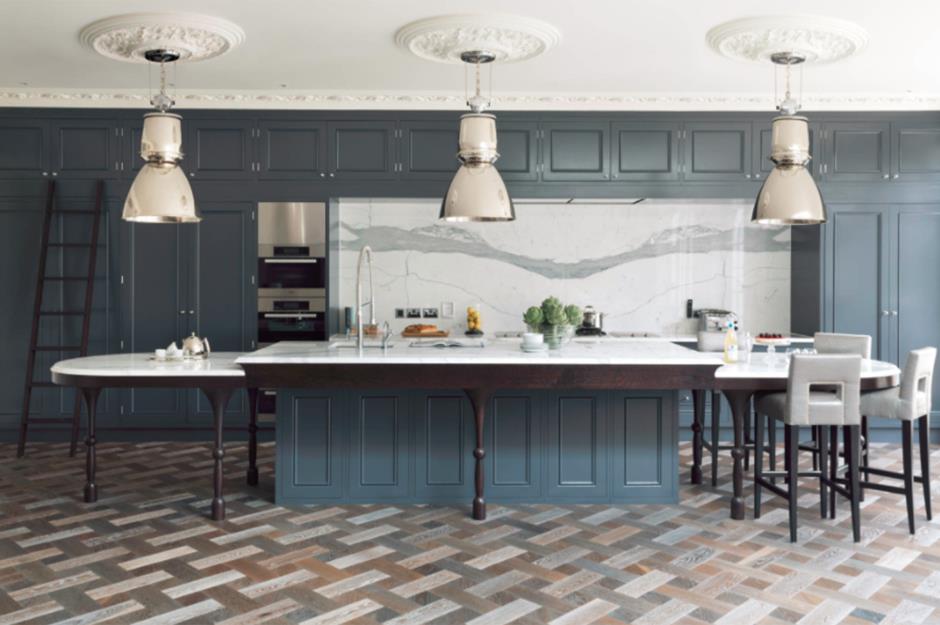 Blue kitchen with chrome pendant lights and silver metal bar stools  