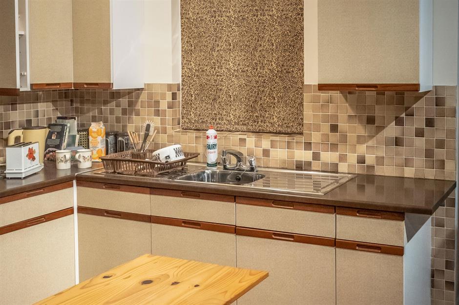 Kitchen with white stone countertops, solid wood cabinets, and vintage tile  on the walls Stock Photo - Alamy