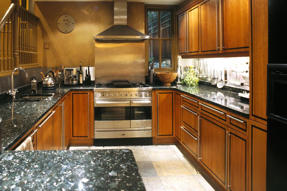 A small kitchen with stainless steel appliances, white cabinets, and a  natural light colored wood counter top Stock Photo - Alamy