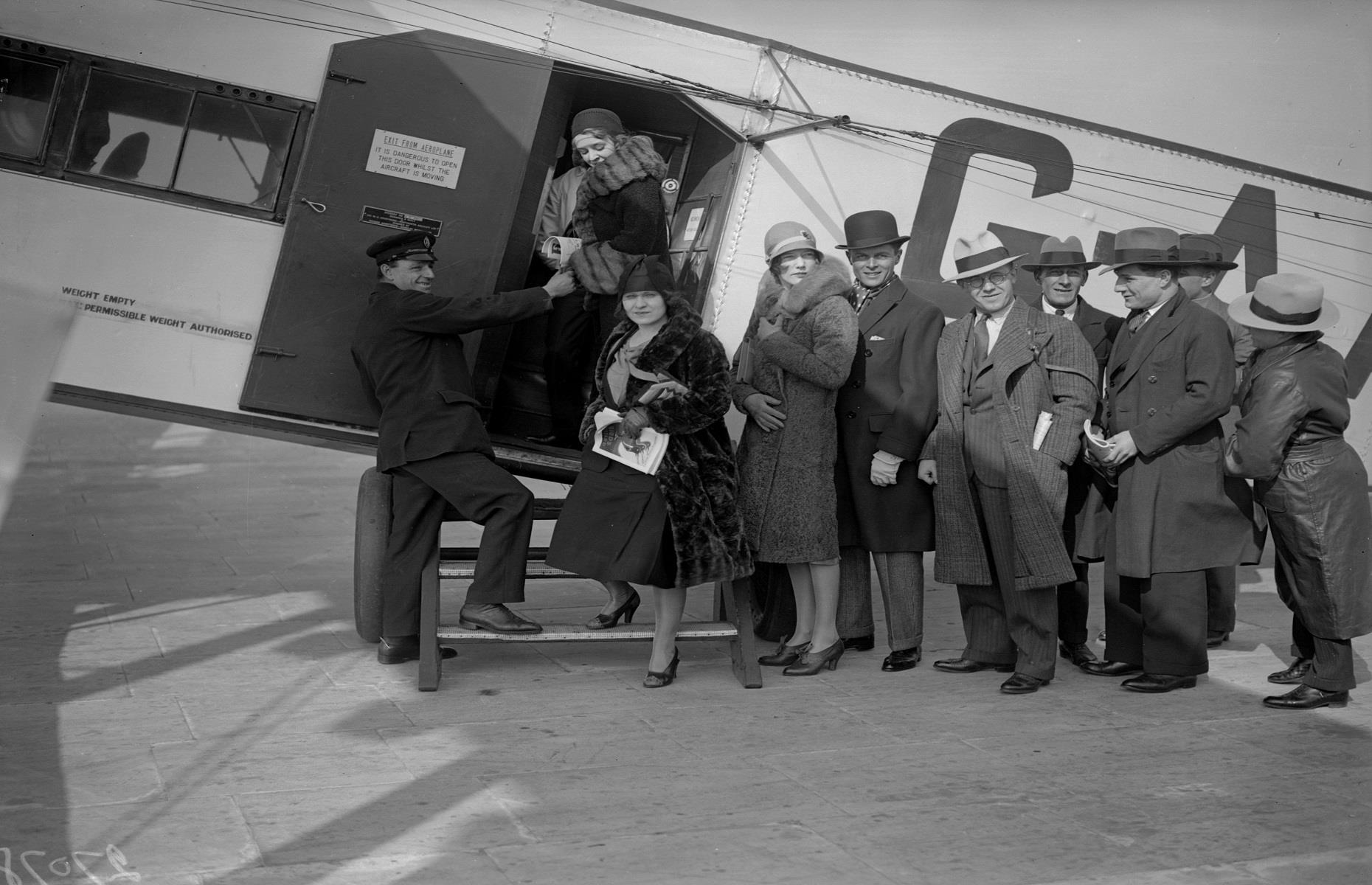 1930s: passengers climb aboard a plane at Croydon Airport, England