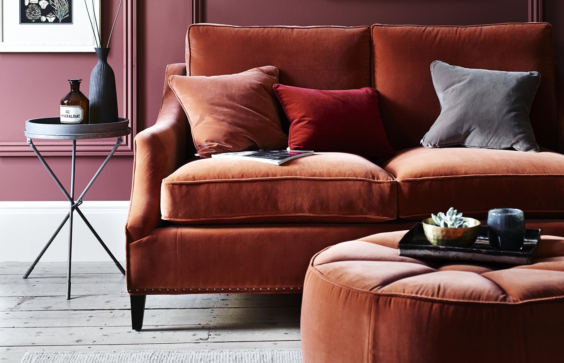 A rust red sofa and footstool 