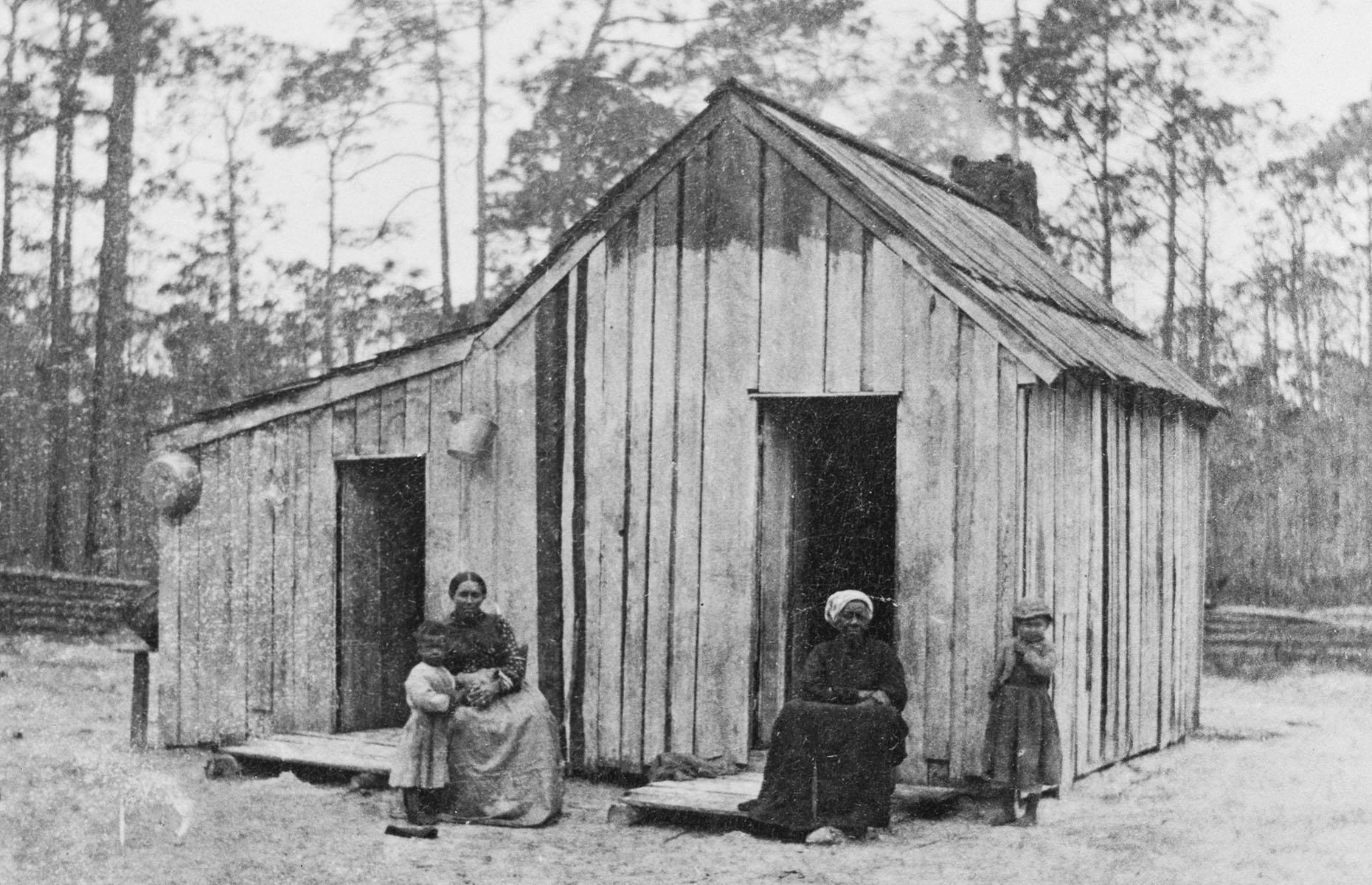 1875: a family outside their wooden cabin