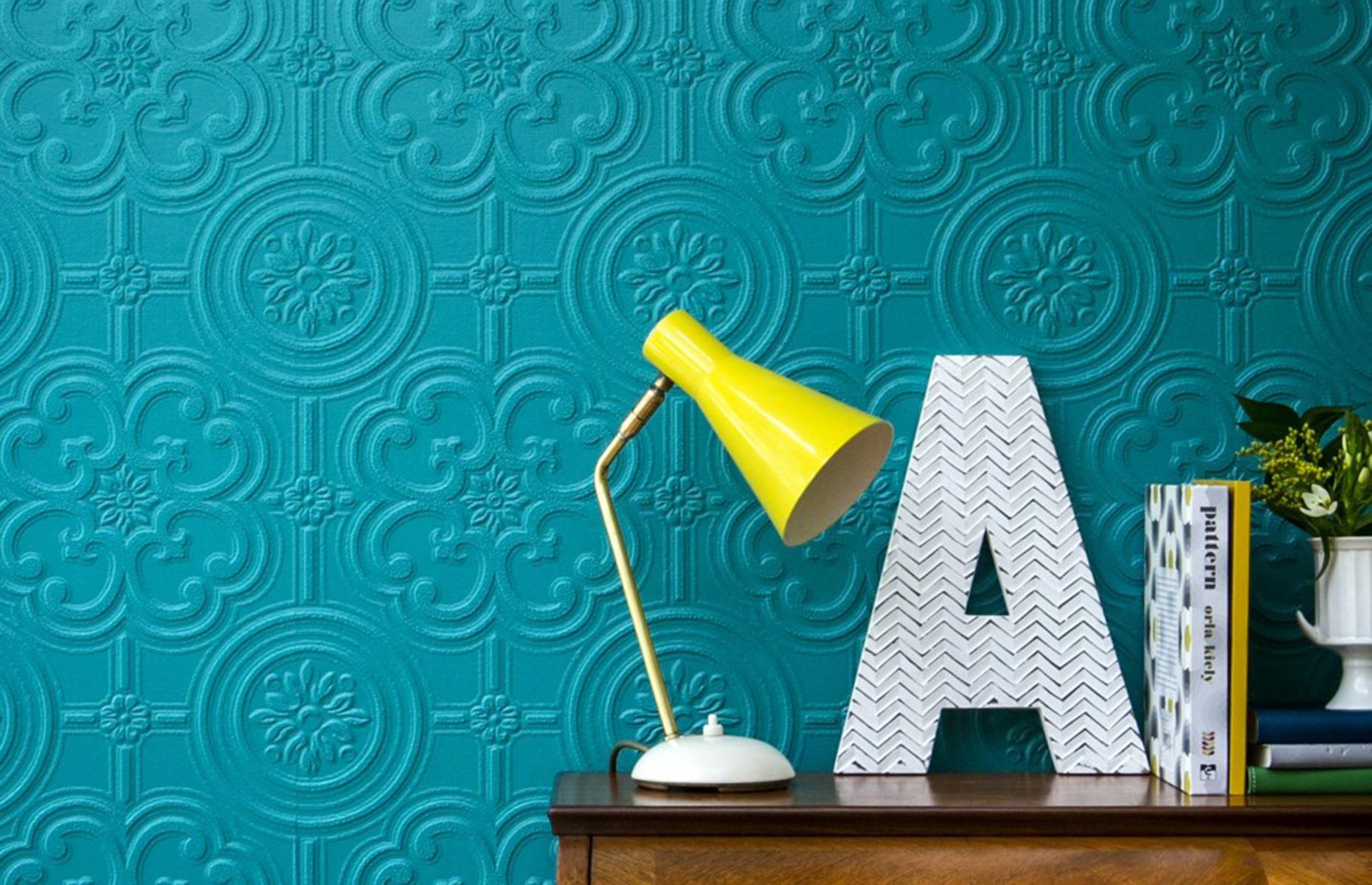 Teal Anaglypta wallpaper with a console table with a yellow lamp in front